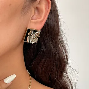 Close-up of vintage square earring with rhinestone butterfly and black enamel detail