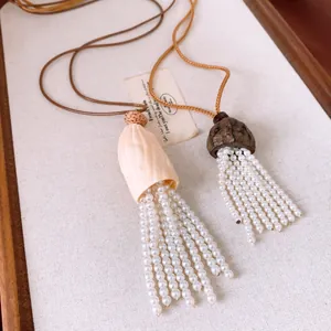 Close-up detail of unique wood shell caps and elegant pearl beaded tassel necklaces