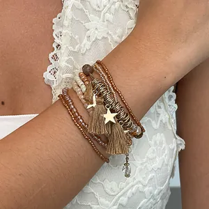 Dettaglio di braccialetti bohémien a strati con perline, ciondoli a stella e nappe