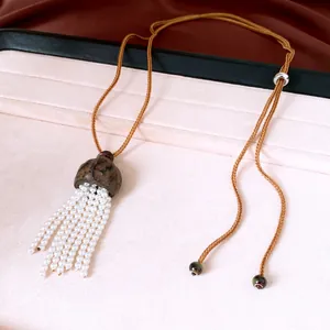 Detail view of pearl tassel necklace featuring a natural wood nut shell pendant.
