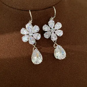 Elegante Zirkonia-Blumenohrringe mit birnenförmigen Anhängern auf braunem Display