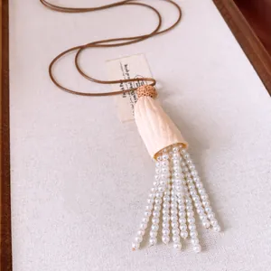 Detail shot of pearl tassel necklace with leather cord and natural shell pendant