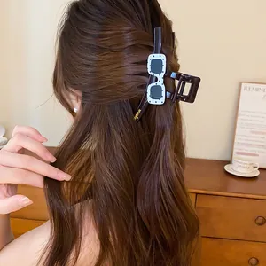 Dettaglio di una grande molletta per capelli coreana con design a occhiali a pois su capelli.