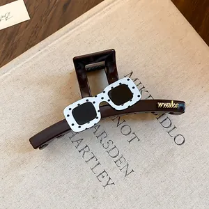 Dettaglio di un fermaglio per capelli a pois stile occhiali con scritte wwake dorate