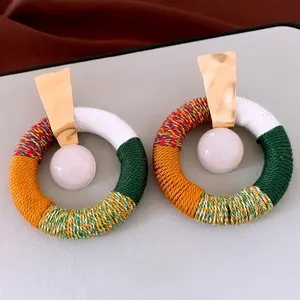Ethnic style cotton rope hoop earrings with white resin bead and gold metal studs.