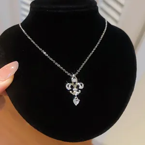 Gros plan détaillé d'un collier avec pendentif en zircon fleur de lys et goutte de cœur