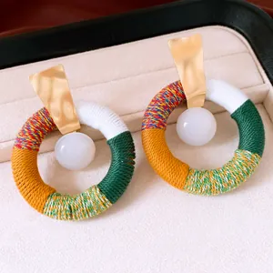 Gros plan détaillé de boucles d'oreilles rondes en corde de coton multicolore et résine