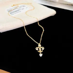 Vue détaillée d'un collier plaqué or 14K avec pendentif fleur de lys et cœur en zircon
