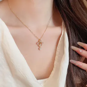 Gros plan du collier plaqué or 14K avec pendentif fleur de lys et cœur serti de zircons.