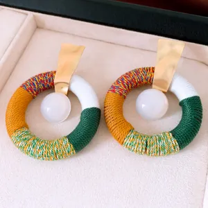 Gros plan de boucles d'oreilles ethniques avec corde de coton et perles en résine blanche
