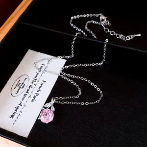Elegante Silberkette mit rosa Zirkonia-Blumenanhänger auf dekorativem Schachtel-Hintergrund