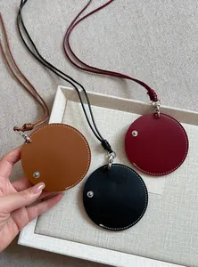 Macro view of circular leather eyeglass holder necklaces in brown, black, and red.