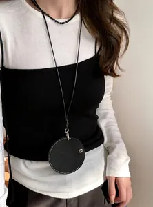 Detail view of a minimalist black circular leather pendant glasses holder necklace.