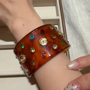 Amber resin cuff bracelet with multi-colored rhinestones and gold spiral studs