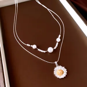 Elegant layered silver necklace with pearls and a sparkling daisy flower pendant detail
