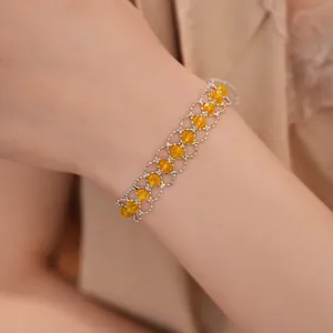Vue détaillée d'un bracelet en maille argentée orné de perles de verre jaunes