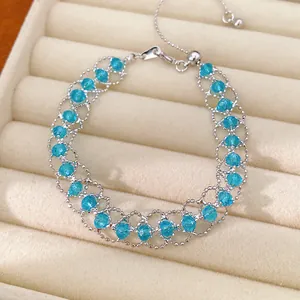 Gros plan d'un bracelet en maille d'argent ajustable avec des perles de verre bleues.