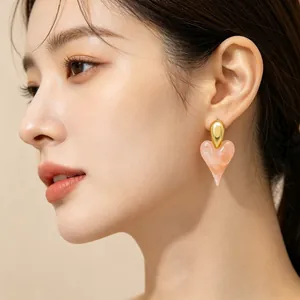 Elegant detail view of a pink resin heart-shaped earring with 18K gold plated stud worn by a model