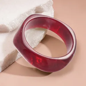 Close-up of a translucent dark red resin bangle with unique geometric rounded square shape.