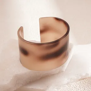 Close-up detail of a stylish wide tortoiseshell pattern acrylic cuff bracelet on stone