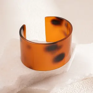 Close-up detail showing the glossy amber tortoiseshell texture of a resin cuff bracelet.