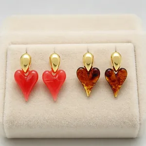 Detail view of vintage heart resin earrings in red and amber with 18K gold plating.