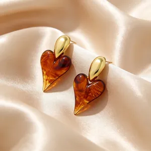 Macro detail of vintage heart-shaped resin earrings with 18K gold-plated finish