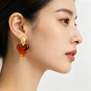Professional close-up of vintage heart resin earring with 18K gold plated stud on model