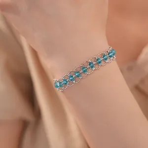Détail montrant les perles en verre bleu tressées et les accents argentés au poignet