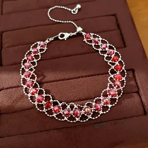 Bracelet élégant en perles de verre rouges, maille tressée et fermoir ajustable.
