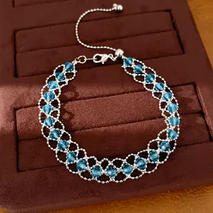 Gros plan d'un bracelet en maille argentée orné de délicates perles de verre bleues.