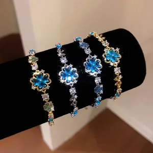 Bracelet à fleurs en zircone bleu glacé étincelant, tons or et argent, sur support noir.