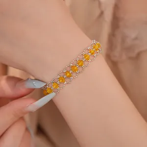Gros plan détaillé d'un bracelet tissé en maille argentée avec perles de verre jaunes