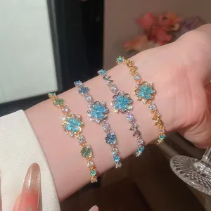 Detailed view of four delicate blue and green zircon flower bracelets on a wrist.
