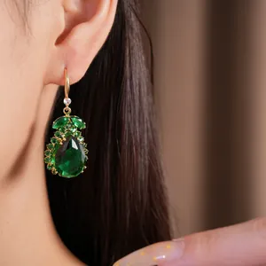 Nahaufnahme von eleganten Vintage-Goldohrringen mit smaragdgrünen Zirkon-Tropfen