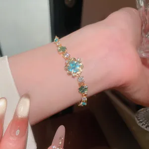 Close-up of elegant gold flower bracelet with blue and green cubic zirconia