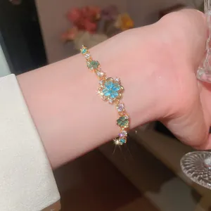 Detailed view of gold bracelet with ice blue flower and green clover zircon accents.