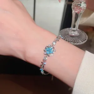 Detailed view of a silver bracelet with a blue zircon flower and sparkling stones.