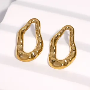 Dettaglio ravvicinato di orecchini a lobo minimalisti in oro geometrici e irregolari