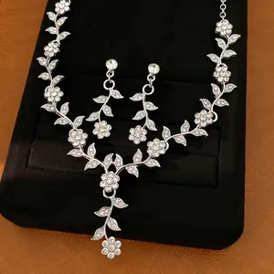 Close-up of elegant silver-colored floral leaf necklace and earrings with rhinestones