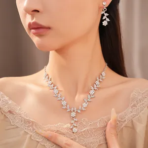 Detail shot of sparkling floral leaf rhinestone necklace and earring jewelry set on model.