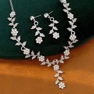 Detailed view of elegant silver-colored necklace and earring set with floral rhinestone motifs