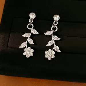 Close-up of elegant silver leaf and flower earrings with sparkling rhinestones