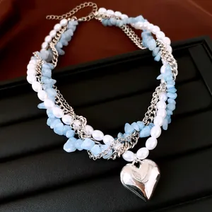 Vue détaillée du collier multicouche avec perles, pierres bleues et cœur en argent.