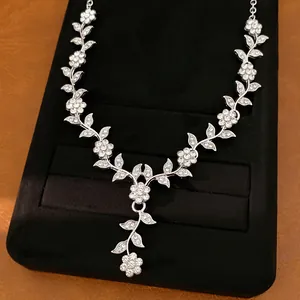 Macro detail of silver necklace featuring intricate rhinestone floral and leafy motifs