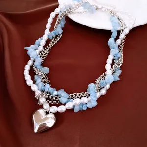 Vue détaillée du collier multicouche avec perles, pierres bleues et pendentif cœur.