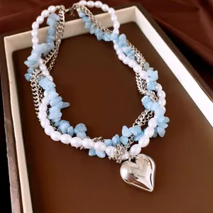 Gros plan d'un collier multi-rangs avec perles, pierres bleues et pendentif coeur