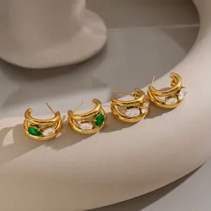 Vue détaillée de boucles d'oreilles en C plaquées or 18K avec zircons verts et blancs