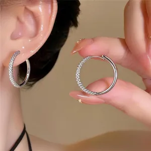 Close-up detail of silver hoop earrings with micro-pave stones and a smooth finish.
