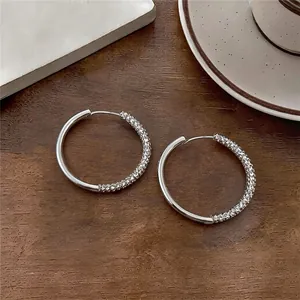 Close-up view of minimalist asymmetrical silver hoop earrings with sparkling pave crystal details